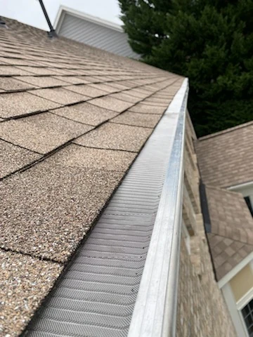 Gutter guard installed along a residential roof edge